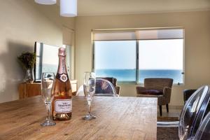 a bottle of champagne and two glasses on a table at Sea Spray A308 by Host Agents in Bloubergstrand