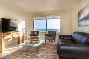 a living room with a couch and a tv at Sea Spray A308 by Host Agents in Bloubergstrand