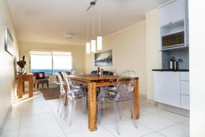 a kitchen and dining room with a wooden table and chairs at Sea Spray A308 by Host Agents in Bloubergstrand