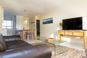 a living room with a couch and a flat screen tv at Sea Spray A308 by Host Agents in Bloubergstrand
