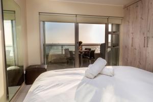 a bedroom with a bed with a view of a table at Sea Spray A308 by Host Agents in Bloubergstrand +13 photos