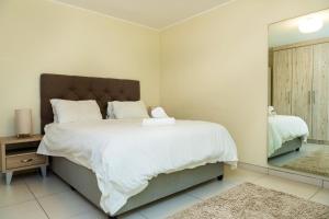 a bedroom with a large bed and a mirror at Sea Spray A308 by Host Agents in Bloubergstrand