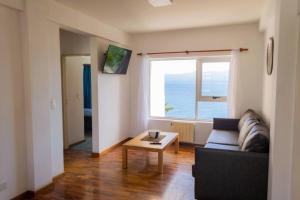 ein Wohnzimmer mit einem Sofa, einem Tisch und einem Fenster in der Unterkunft Dpto. Centrico con Vista al Lago in San Carlos de Bariloche