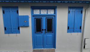 une porte bleue et deux fenêtres sur un bâtiment dans l'établissement Cozy Traditional 1 Bedroom Home Omodos Village, à Omodos