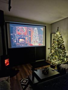 a living room with a christmas tree and a large tv at Chilloutzonе - Будинок з безкоштовним джакузі та кінотеатром in Slavske