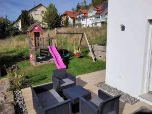 un patio trasero con un columpio y un parque infantil en Ferienwohnung Albliebe en Meßstetten