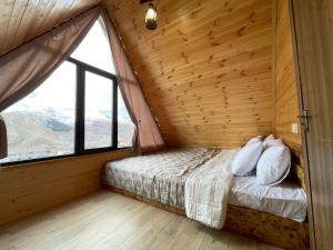 łóżko w pokoju z dużym oknem w obiekcie Cozy Home Kazbegi w mieście Stepancminda