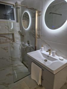 een witte badkamer met een wastafel en een douche bij Stan na dan Jelica Stanivuković in Šid