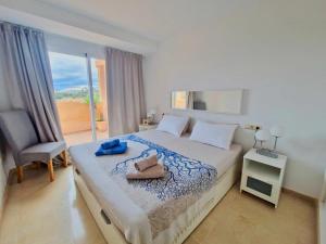 a bedroom with a bed with a chair and a window at SR Santa Maria Golf Marbella with Sea Views in Marbella