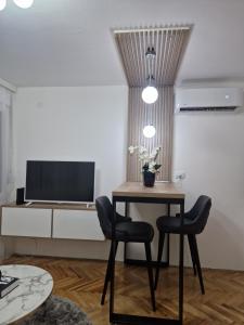 een kamer met een tafel en twee stoelen en een televisie bij Stan na dan Jelica Stanivuković in Šid