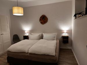 um quarto com uma cama com lençóis brancos e almofadas em Landhof Belka em Hoyerswerda