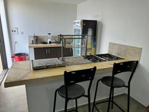 a kitchen with a counter with two bar stools at Se Alquila Hermosa Cabaña Turquesa in Lebrija