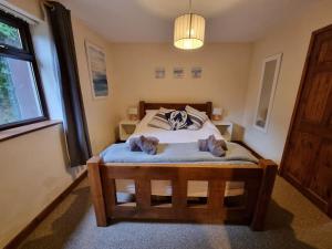 two cats laying on a bed in a bedroom at Cosy Cottage in Edern, Morfa Nefyn, Golf, Near Ty Coch in Ederyn