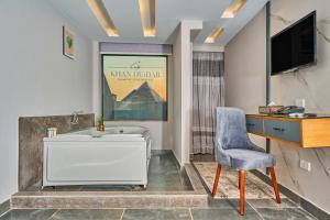 a bathroom with a tub and a chair and a television at Khan Duidar Inn - Pyramids View Rooftop in Cairo
