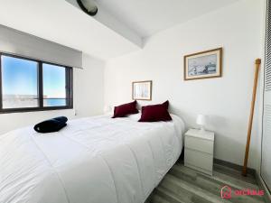 a bedroom with a large white bed with red pillows at Bello Amanecer en La Concha in Oropesa del Mar