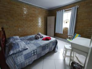 a bedroom with a bed with a stuffed animal on it at CASA DE PRAIA ILHA in Araranguá