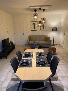 einen Tisch mit Stühlen und Weingläsern darauf im Wohnzimmer in der Unterkunft Appartement de charme in Fleurus