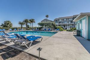a swimming pool with lounge chairs next to a building at First Floor Condo - Walking distance to beach and pools! in Harbor Island