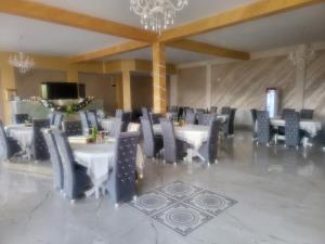 uma sala de jantar com mesas e cadeiras e um lustre em Soimii Bucovinei Residence em Vatra Moldoviţei