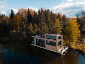 zwei Menschen stehen auf einem Haus auf einem Dock im Wasser in der Unterkunft MiniBora Le beaumier - Cantons-de-l'Est in Bury