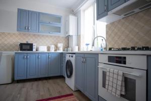 a kitchen with blue cabinets and a washing machine at Pretty House Apartment in Gura Humorului +6 photos