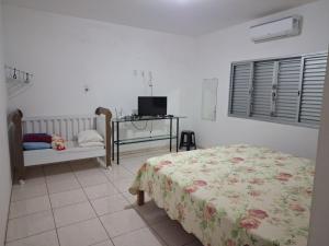 Schlafzimmer mit einem Bett, einem Tisch und einem TV in der Unterkunft Casa para temporada primavera na canastra in São Roque de Minas