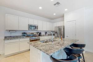 una cocina con armarios blancos y una barra con 2 taburetes en The Spotless 2 Story en Phoenix