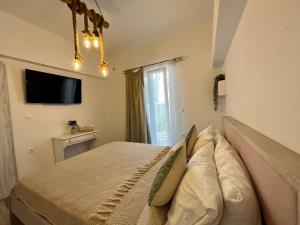 a bedroom with a bed with pillows and a television at Aleria Central Apartment 2 in Naxos Chora
