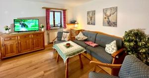 a living room with a couch and a tv at Haus Bergwelten Ramsau - Hintermühle in Ramsau