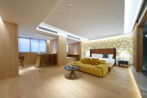 a hotel room with a bed and a yellow couch at Encounter Hotel - West Lake Hefang Street in Hangzhou