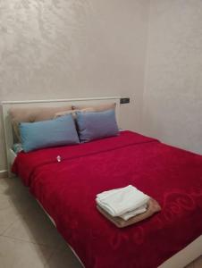 - un lit avec des draps rouges et des oreillers bleus et des serviettes dans l'établissement Bel appartement calme est bien équipé, à Meknès