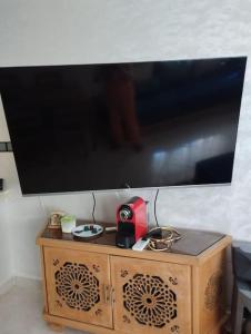 TV a schermo piatto a parete con armadio in legno di Bel appartement calme est bien équipé a Meknès