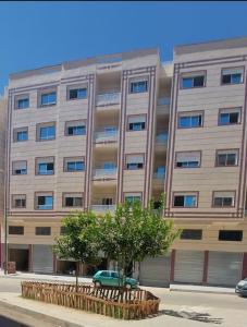 un grand bâtiment avec une voiture verte devant lui dans l'établissement Bel appartement calme est bien équipé, à Meknès