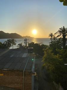 una puesta de sol sobre el océano con un edificio y palmeras en Sunset View, Taganga, en Taganga