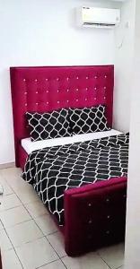 a bed with a red headboard in a room at Résidence Sighaka - Suite Royale - WiFi, Gardien, Parking in Douala