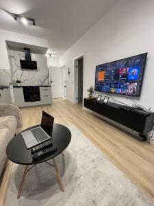 - un salon avec un ordinateur portable installé sur une table et une télévision dans l'établissement AirPort Apartment, à Varsovie
