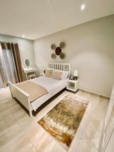 um quarto com uma grande cama branca e um tapete em Petit Charlie @ Forest view em Banjul