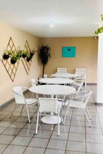 uma sala de jantar com mesas brancas e cadeiras brancas em Casa Canasvieiras Florianópolis com piscina e mar em Florianópolis