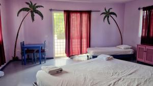 um quarto com duas camas e duas palmeiras em Il Triangolo Hostel em Las Galeras