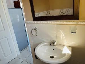 uma casa de banho com um lavatório branco e um espelho. em Bachelor suite in Rustenburg em Rustenburg