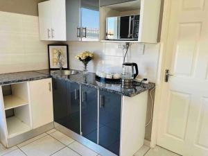 a small kitchen with blue cabinets and a sink at Bachelor suite in Rustenburg in Rustenburg