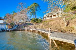 a wooden dock in the water with a building in the background at Waterfront Lake Tillery Home with Incredible Views! in Mount Gilead