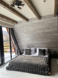 ein Schlafzimmer mit einem großen Bett und einem großen Fenster in der Unterkunft Valea Mosului - Charme A Frame in Petroşani