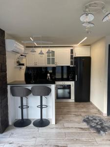 a kitchen with white cabinets and black appliances at Valea Mosului - Charme A Frame in Petroşani
