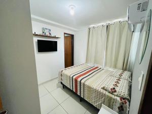 ein kleines Schlafzimmer mit einem Bett und einem TV in der Unterkunft Apto NOVO de 2 quartos a 50m da praia do bessa in João Pessoa