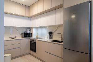 a kitchen with white cabinets and a stainless steel refrigerator at Flexible SelfCheckIns 63 - Zagreb - Parking - Loggia - Brand New in Zagreb