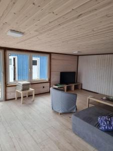 uma sala de estar com um sofá e uma televisão e algumas janelas em Mulseryd em Bottnaryd
