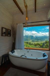 uma banheira num quarto com uma grande janela em Pousada Colina do Sol em Urubici