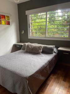 uma cama num quarto com uma grande janela em Casa Buda em Villa Gesell