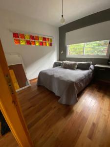 um quarto com uma cama e piso em madeira em Casa Buda em Villa Gesell